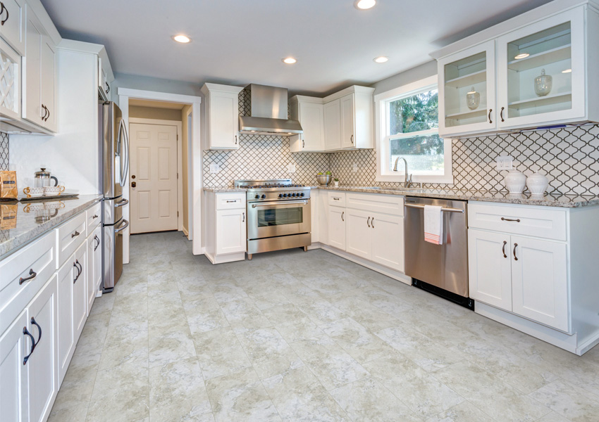 stone look luxury vinyl tile flooring in kitchen with white cabinets and tile backsplash